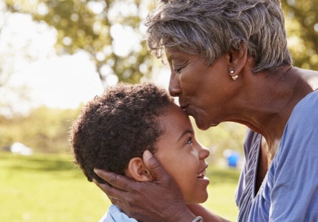 Close Up Of Grandmother Kissing Grandson In Park